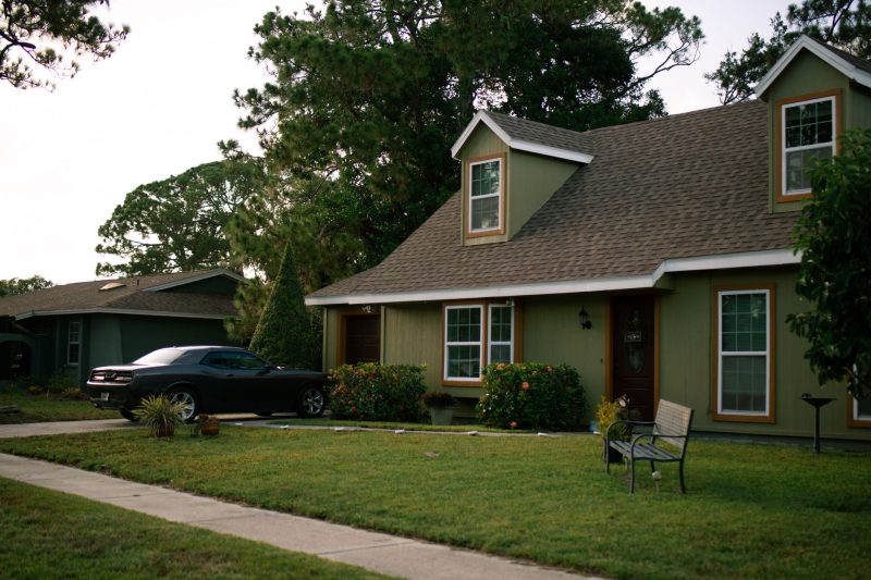 Suburban home with a manicured lawn, parked car, and charming exterior, conveying a sense of residential comfort.