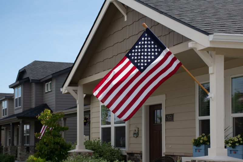 Vibrant American flag waving in front of a stylish suburban house on a sunny day.