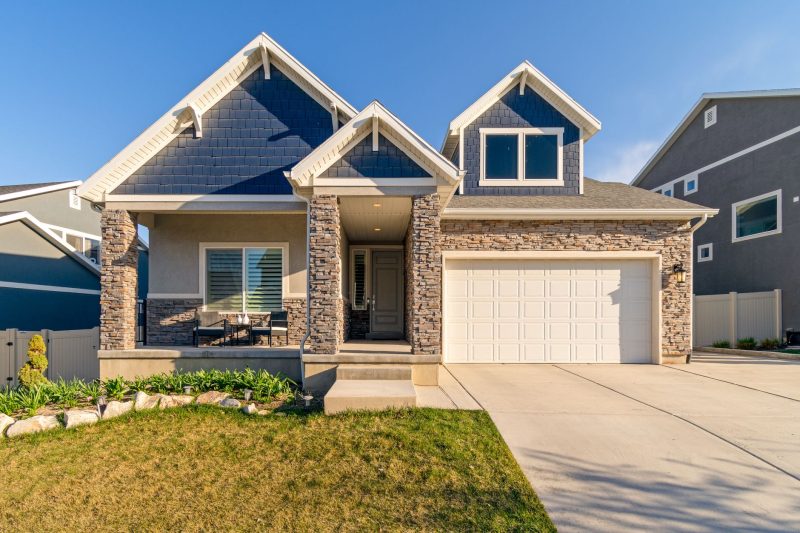 Charming modern suburban home with a stone facade and a well-kept lawn.